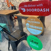 We Deliver, Doordash, Grubhub and Uber Eats signs on restaurant door, New York City.