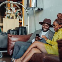 wealthy couple with smartphone in hotel lounge. - travel stock pictures, royalty-free photos & images