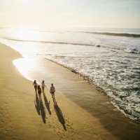 wide aerial shot of family walking on tropical beach at sunrise - travel stock-fotos und bilder