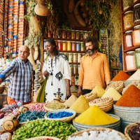 wide shot couple talking to spice shop owner in the souks of marrakech - travel stock pictures, royalty-free photos & images