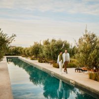 wide shot couple walking along edge of pool at boutique luxury resort - travel stock pictures, royalty-free photos & images