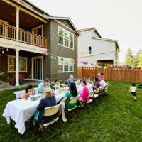wide shot family sharing a meal in backyard during birthday party - garden decoration stockfoto's en -beelden