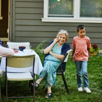 wide shot grandmother at table in backyard during family birthday party - garden decoration stock pictures, royalty-free photos & images