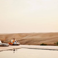 wide shot man sitting beside pool and working on laptop at desert camp - travel stock pictures, royalty-free photos & images