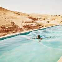 wide shot man swimming in pool at moroccan desert camp during vacation - travel stock pictures, royalty-free photos & images