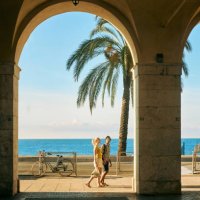 wide shot of a couple on holiday walking under an archway on the promenade des anglais in nice, france - travel stock pictures, royalty-free photos & images