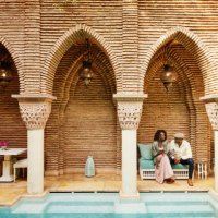 wide shot of couple holding hands while sitting in courtyard of luxury hotel - travel stock pictures, royalty-free photos & images