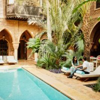 wide shot of couple sitting by pool in courtyard of luxury hotel - travel stock pictures, royalty-free photos & images