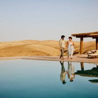 wide shot of couple walking around pool at desert camp at sunrise - travel stock pictures, royalty-free photos & images