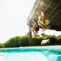 wide shot of gay couple jumping into pool at luxury tropical villa while on vacation - travel photos et images de collection