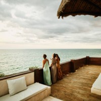 wide shot of laughing female friends standing on deck of luxury hotel suite looking at ocean and sunset - fashion stock pictures, royalty-free photos & images