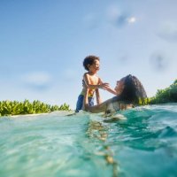 wide shot of laughing mother and son playing in pool at tropical resort - travel stock pictures, royalty-free photos & images