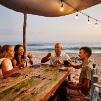 wide shot of smiling family enjoying drinks at tropical beach restaurant - travel stock pictures, royalty-free photos & images
