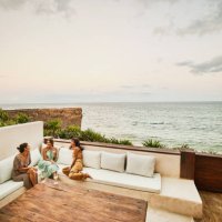 wide shot of smiling female friends relaxing on deck of luxury hotel suite at sunset - travel stock pictures, royalty-free photos & images