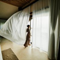 wide shot of woman standing in luxury hotel suite looking at view with curtains blowing in wind - travel stock pictures, royalty-free photos & images