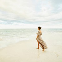 wide shot of woman walking on beach and enjoying sunset at tropical resort - fashion stock pictures, royalty-free photos & images