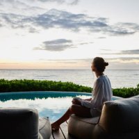 wide shot of woman watching sunrise while sitting poolside at luxury suite at tropical resort - travel stock-fotos und bilder