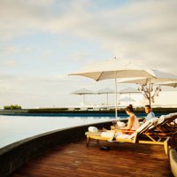 wide shot of woman working on laptop in lounge chair by pool at resort - travel stock pictures, royalty-free photos & images