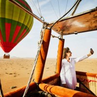wide shot woman taking selfie during sunrise hot air balloon ride - travel stock-fotos und bilder