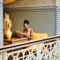 wide shot woman working on laptop in alcove of ornately decorated riad - travel stockfoto's en -beelden