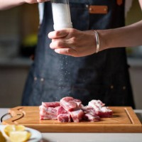 woman adding salt on slicied pork ribs meat on the cutting board - food stock pictures, royalty-free photos & images
