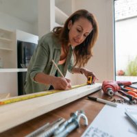 woman at home working on a diy project and measuring a piece of wood - home decoration stock pictures, royalty-free photos & images