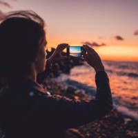 woman at the beach photographing the sunset - travel stock pictures, royalty-free photos & images
