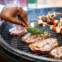 woman basting meat on barbecue with fresh herbs - food stock pictures, royalty-free photos & images