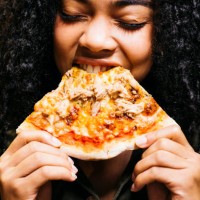 woman biting a slice of a pizza - junk food stock pictures, royalty-free photos & images
