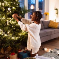 woman black ethnicity decorating a christmas tree - home decoration stock pictures, royalty-free photos & images