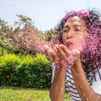woman blowing pink glitter from palms - garden decoration stockfoto's en -beelden