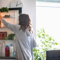 woman by the open fridge taking a bunch of parsley - food stock pictures, royalty-free photos & images