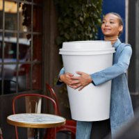 woman carrying large disposable coffee cup outside cafe - junk food stock pictures, royalty-free photos & images