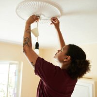 woman connecting light bulb on ceiling at home - home decoration stock pictures, royalty-free photos & images