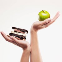 woman cupping green apple above chocolate bars - junk food stock pictures, royalty-free photos & images