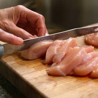 woman cutting raw chicken on a wooden cutting board - food stock pictures, royalty-free photos & images