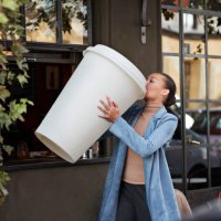 woman drinking coffee from large disposable cup at take away counter of cafe - coffee stock pictures, royalty-free photos & images