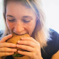 woman eating a burger - junk food stock pictures, royalty-free photos & images