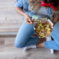 woman eating a poke bowl at home while moving house - junk food stock pictures, royalty-free photos & images