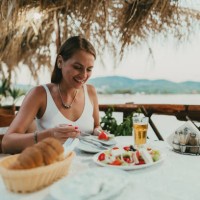 woman eating greek salad in a restaurant at the seaside in greece - food stock pictures, royalty-free photos & images