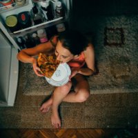 woman eating in front of the refrigerator in the kitchen late night - junk food stock pictures, royalty-free photos & images