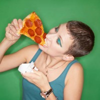 woman eating pizza slice - junk food stockfoto's en -beelden