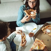 woman eating pizza with family - junk food stock pictures, royalty-free photos & images