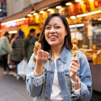 woman eating street food at market - junk food stock pictures, royalty-free photos & images