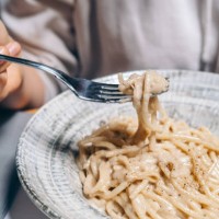 woman eats spaghetti in cheese sauce with black pepper at restaurant . traditional roman pasta cacio e peppe in italy, italian cuisine recipes - food stock pictures, royalty-free photos & images