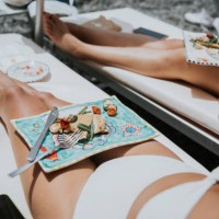 woman enjoy a luxury holiday experience - eating lunch from the comfort of a sun lounger on a beach - food stock pictures, royalty-free photos & images
