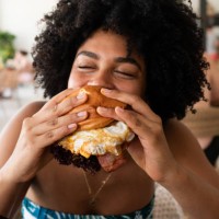 woman enjoying a delicious burger in a restaurant - junk food stock pictures, royalty-free photos & images