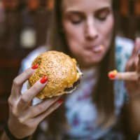 woman enjoying delicious burger - junk food stock pictures, royalty-free photos & images