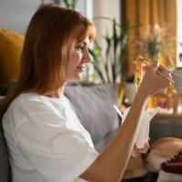 woman enjoying noodles near dog - junk food stock pictures, royalty-free photos & images