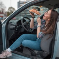 woman enjoys eating pizza on parking lot - junk food stock pictures, royalty-free photos & images